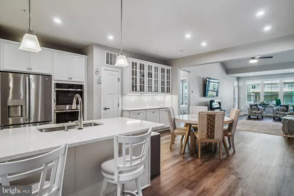 a kitchen with stainless steel appliances a dining table chairs and wooden floor