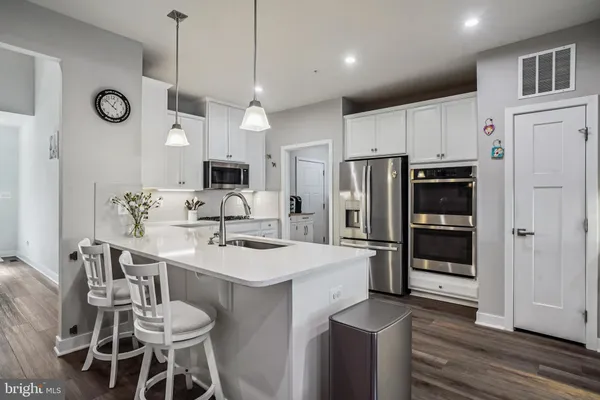 a kitchen with granite countertop a sink cabinets stainless steel appliances and a refrigerator