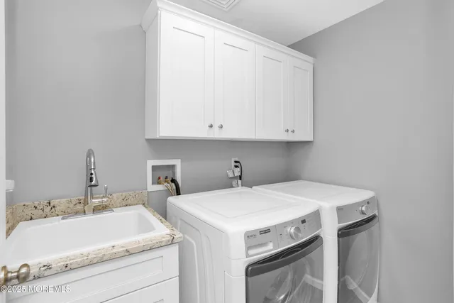 a view of a sink and dishwasher with white cabinets