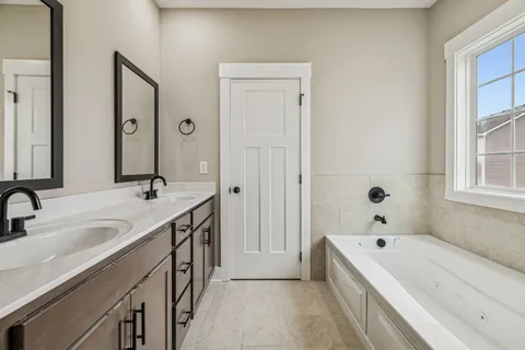 a bathroom with a tub a sink and a large mirror
