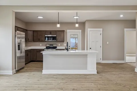 a large kitchen with cabinets wooden floor and stainless steel appliances