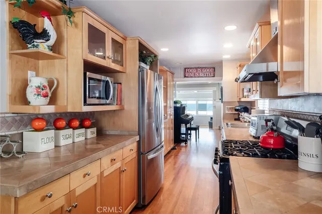 a kitchen with stainless steel appliances granite countertop a refrigerator a sink dishwasher and a stove with wooden floor