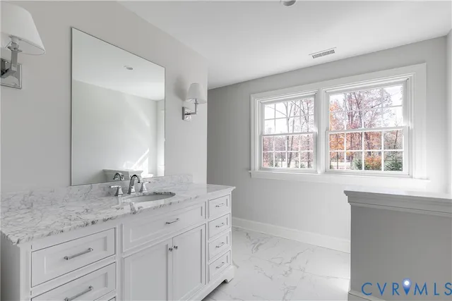 a bathroom with a granite countertop sink and a window