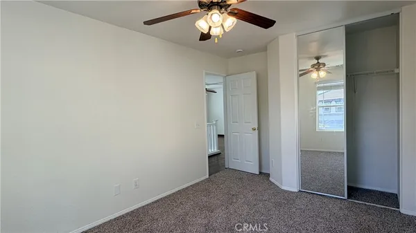 an empty room with closet and a chandelier fan