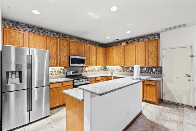 a kitchen with stainless steel appliances granite countertop a refrigerator a stove top oven a sink and dishwasher