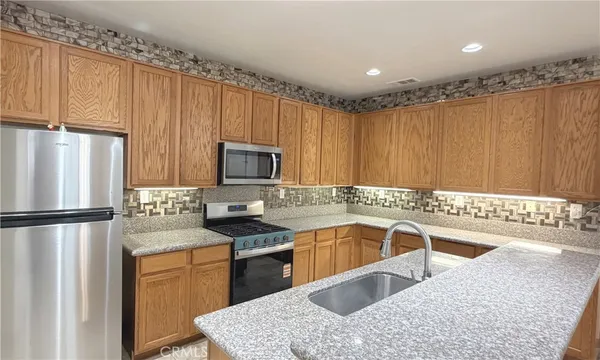 a large kitchen with granite countertop a sink stainless steel appliances and a counter space