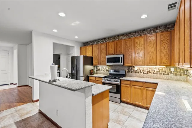 a kitchen with stainless steel appliances granite countertop a sink dishwasher a refrigerator and a stove top oven with wooden floor