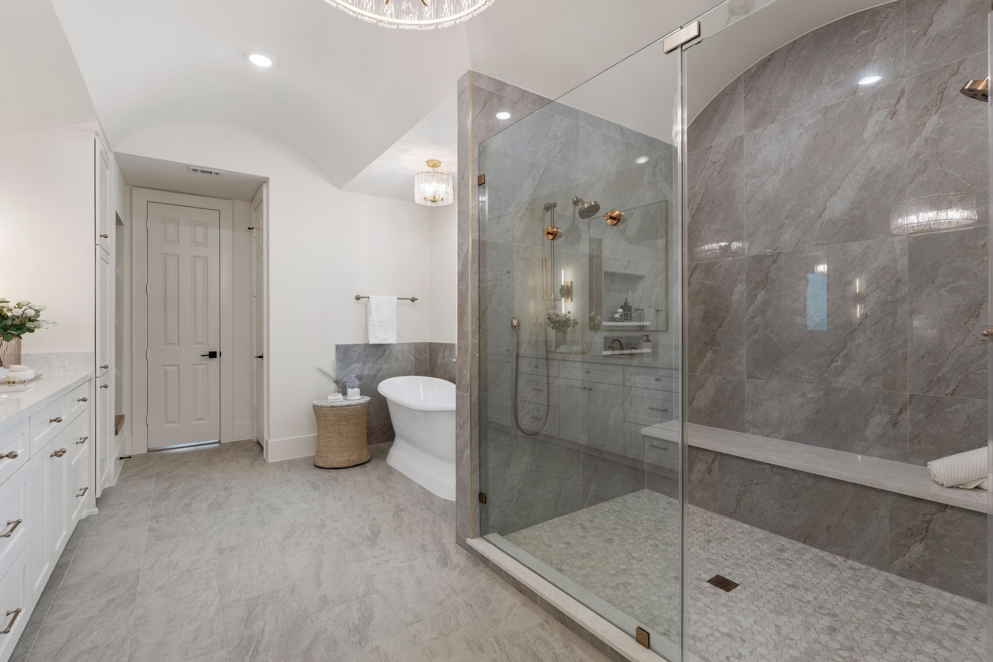 31 Hollymead Drive Spring, TX 77381 - Photo 25 of 50 This luxurious bathroom features a spacious walk-in shower with glass doors, a sleek freestanding bathtub, and elegant marble tiles. Ample counter space and cabinetry provide storage, while modern fixtures add a touch of sophistication.