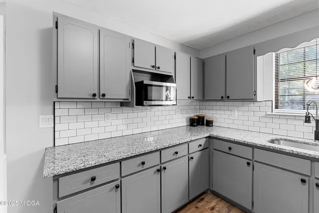 a kitchen with stainless steel appliances granite countertop a sink a stove a microwave and cabinets