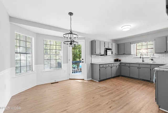 a large kitchen with kitchen island a stove a sink dishwasher a oven with a dining table and wooden floor