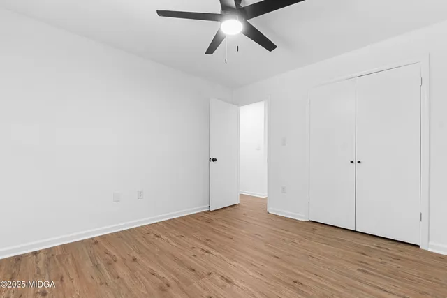 a view of empty room with wooden floor and ceiling fan