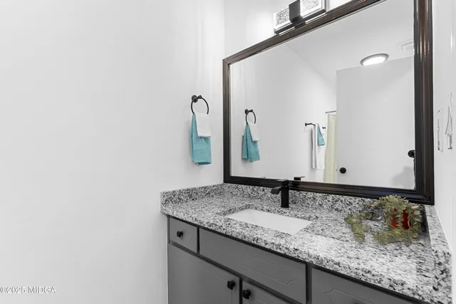 a bathroom with a granite countertop sink and a mirror