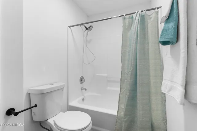a white toilet sitting next to a bath tub