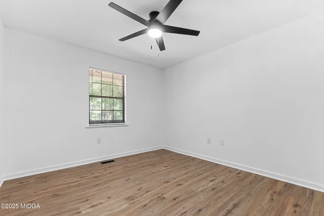 an empty room with wooden floor and windows