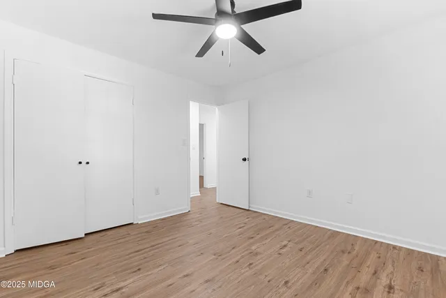 a view of an empty room and chandelier fan