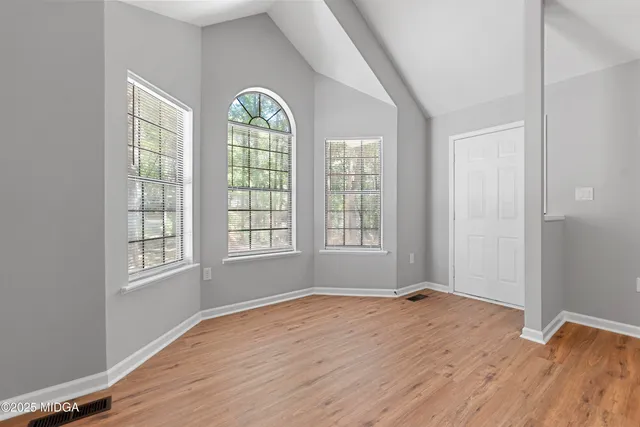 an empty room with wooden floor and windows