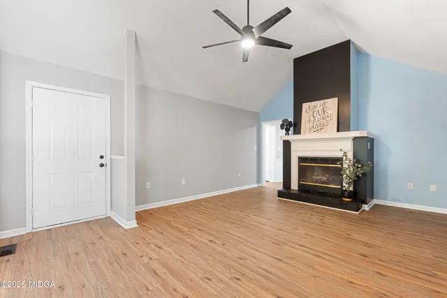 an empty room with windows fireplace and wooden floor