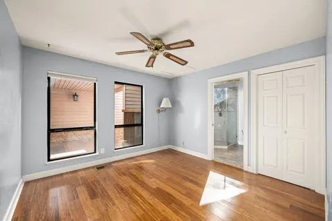 a view of a house with wooden fence and large trees
