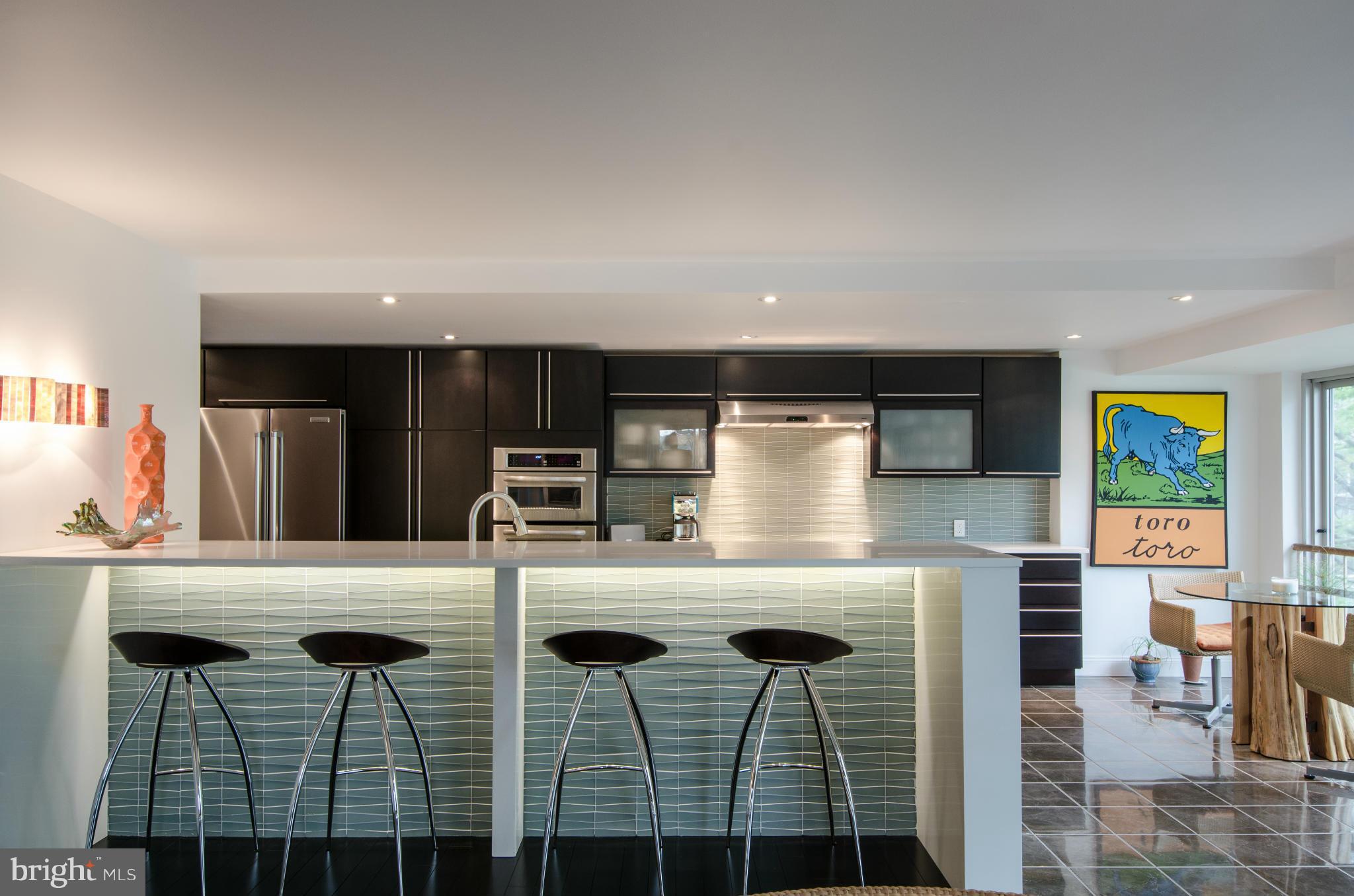550 N Street Southwest, Unit S201 Washington, DC 20024 - Photo 3 of 30 a kitchen with stainless steel appliances kitchen island granite countertop a table chairs and a refrigerator