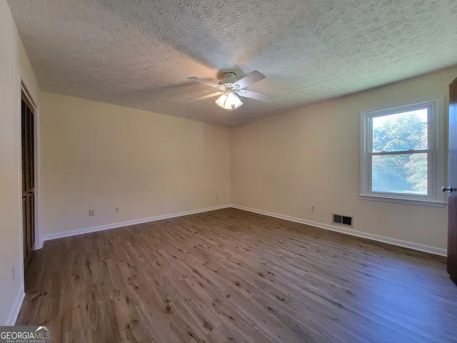 an empty room with wooden floor and windows
