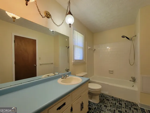 a bathroom with a granite countertop sink toilet a shower and a mirror