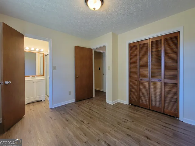 an empty room with wooden floor & windows