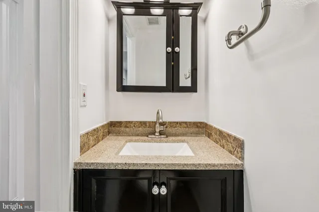 a bathroom with a granite countertop sink and a mirror