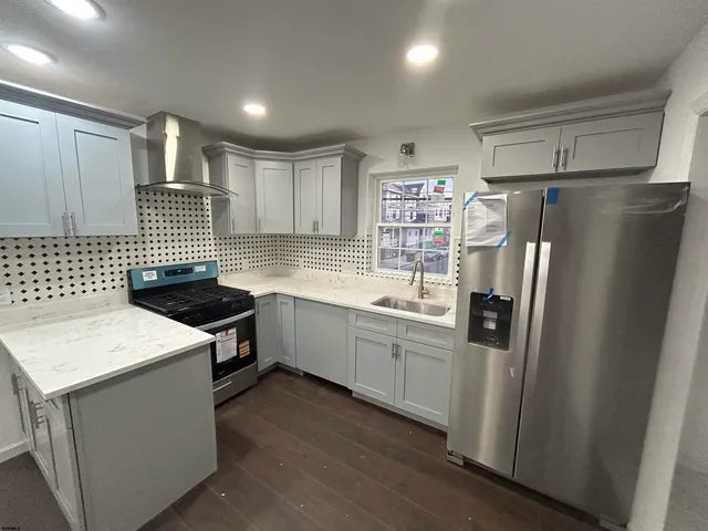 a large kitchen with stainless steel appliances granite countertop a large counter top a stove and a refrigerator