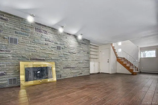 a view of an empty room with wooden floor and a fireplace