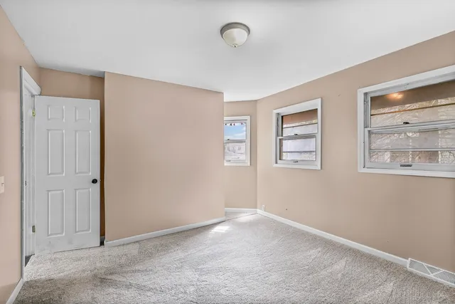 a view of an empty room with windows and closet