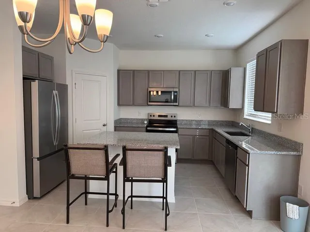 a kitchen with stainless steel appliances granite countertop a refrigerator a stove a sink and a microwave