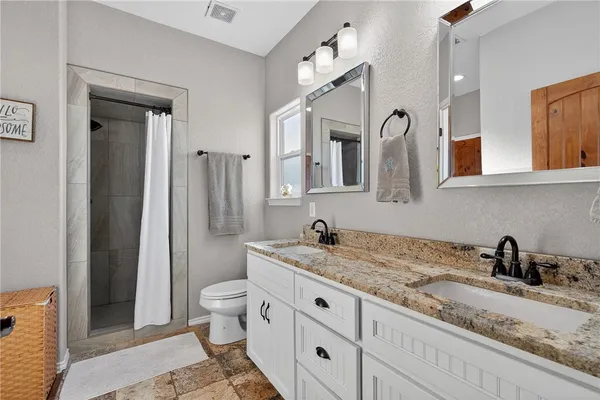 a bathroom with a granite countertop sink a toilet and a mirror