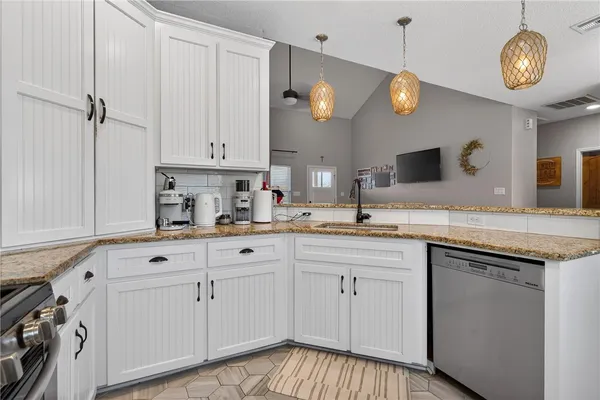 a kitchen with cabinets stainless steel appliances and a chandelier
