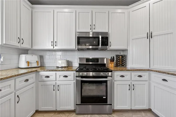 a kitchen with white cabinets and appliances