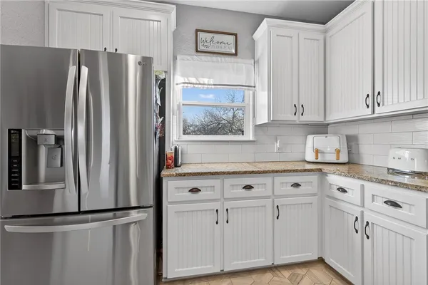 a kitchen with granite countertop white cabinets and stainless steel appliances