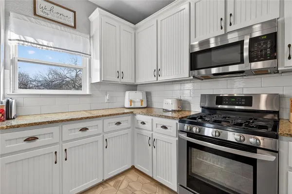 a kitchen with stainless steel appliances white cabinets and a stove a sink
