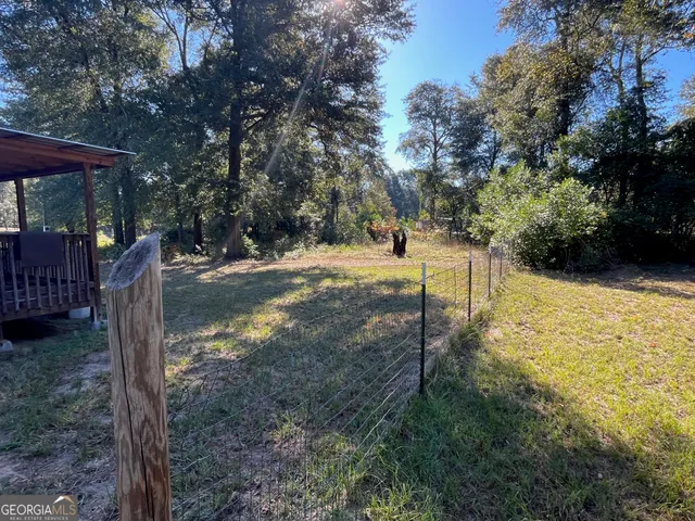a view of a backyard with wooden fence and a tree