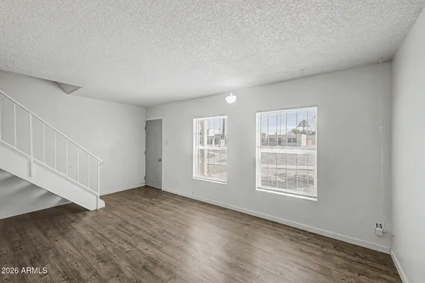 an empty room with wooden floor and windows