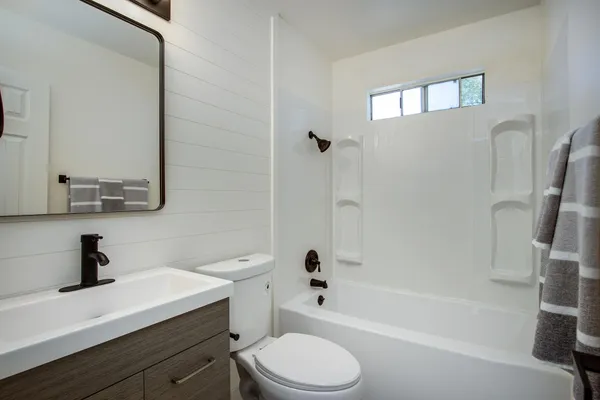 a bathroom with a sink a toilet a mirror and shower