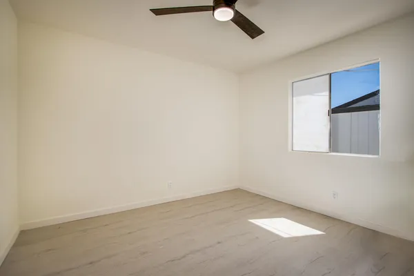 an empty room with a ceiling fan and window