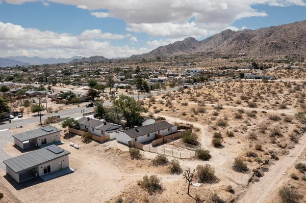 an aerial view of residential house with yard and mountain view in back