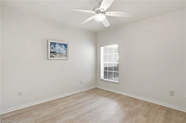 an empty room with a window and ceiling fan
