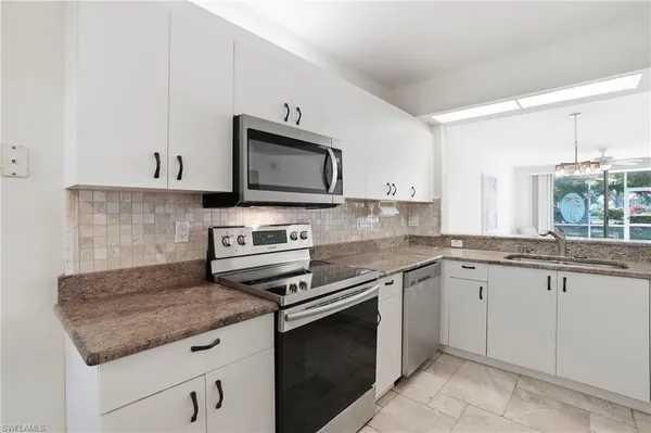 a kitchen with granite countertop a sink stove and microwave