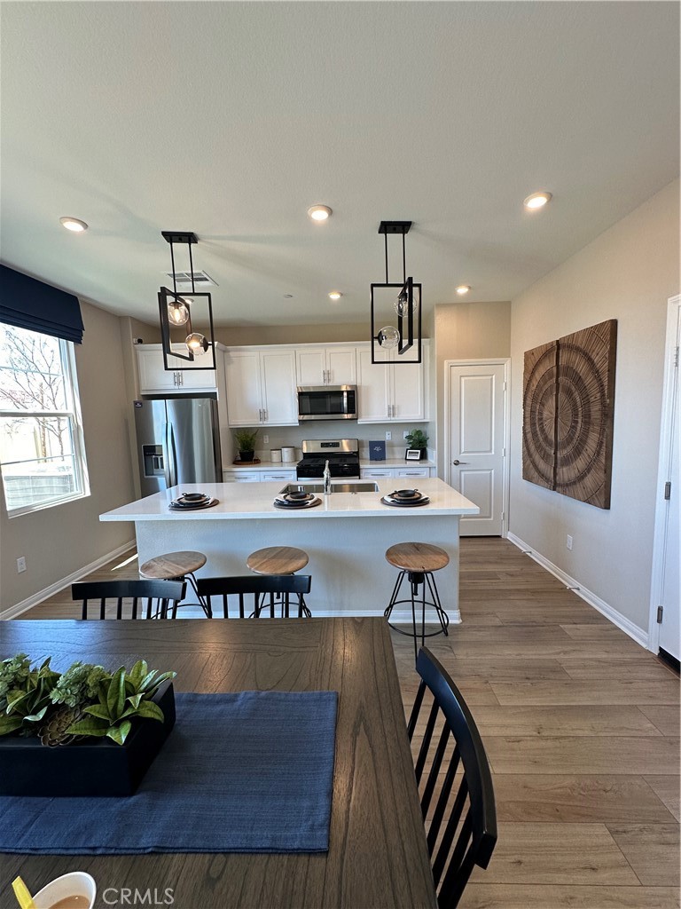 13404 Limestone Drive Yucaipa, CA 92399 - Photo 2 of 4 a view of a kitchen with kitchen island a stove a refrigerator wooden floor and a dining table