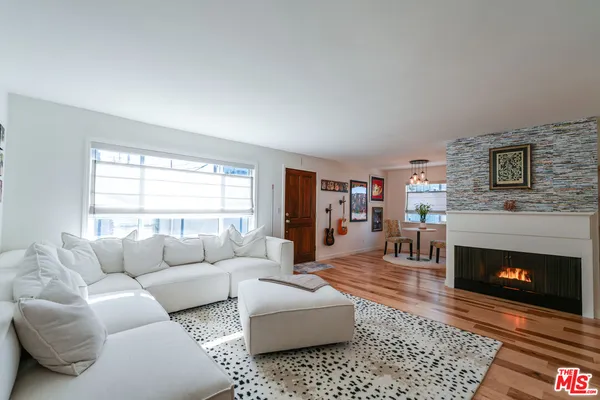 a living room with furniture a rug a fireplace and a window