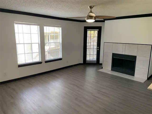an empty room with wooden floor fireplace and windows