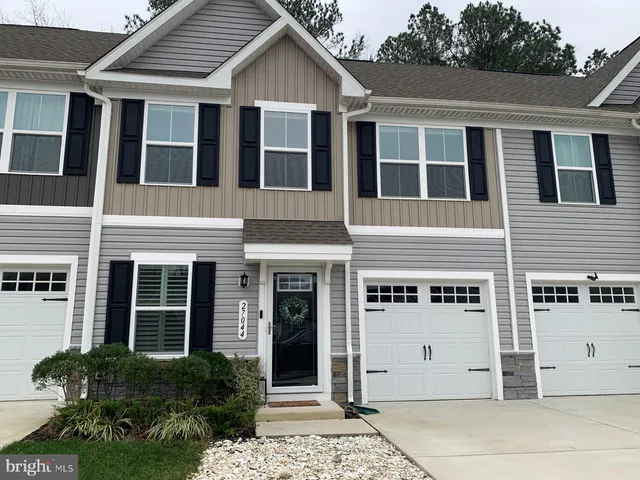 a view of a white house with large windows and potted plants