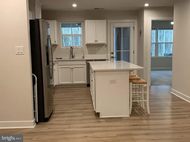 a kitchen with stainless steel appliances a refrigerator a stove a sink and white cabinets