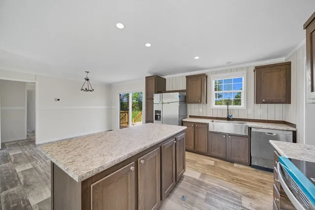 a kitchen with a stove a sink dishwasher and a refrigerator with wooden floor