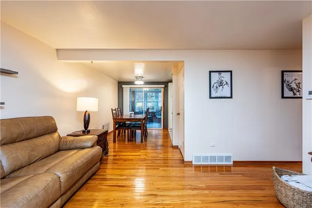 a living room with furniture and a dining table with wooden floor
